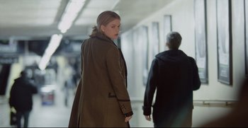 Movie still from “Before We Go” (2014), directed by Chris Evans – A woman in a brown coat is walking down a hallway; Medium shot, Over the shoulder angle