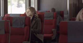 Movie still from “Before We Go” (2014), directed by Chris Evans – A woman sitting on a red seat in a train; Medium shot, Over the shoulder angle