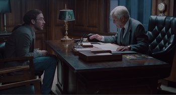 Movie still from “Being John Malkovich” (1999), directed by Spike Jonze – Two men sitting at a table in a room; Medium shot, Over the shoulder angle