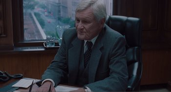 Movie still from “Being John Malkovich” (1999), directed by Spike Jonze – An older man sitting at a desk in front of a window; Medium shot, Over the shoulder angle