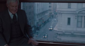 Movie still from “Being John Malkovich” (1999), directed by Spike Jonze – A man in a suit looking out of a window at a busy street; Medium shot, Over the shoulder angle