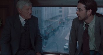 Movie still from “Being John Malkovich” (1999), directed by Spike Jonze – Two men in business suits sitting next to each other on a bus; Medium shot, Over the shoulder angle