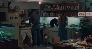 Movie still from “Being John Malkovich” (1999), directed by Spike Jonze – A group of people and a dog in a kitchen; Wide shot, High angle