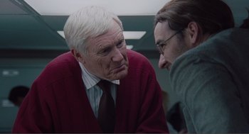 Movie still from “Being John Malkovich” (1999), directed by Spike Jonze – An older man and a younger man are talking to each other; Medium shot, Over the shoulder angle