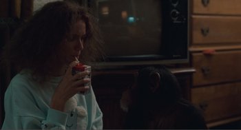 Movie still from “Being John Malkovich” (1999), directed by Spike Jonze – A woman holding a drink in front of a chimpanzee; Medium shot, Over the shoulder angle