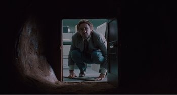 Movie still from “Being John Malkovich” (1999), directed by Spike Jonze – A man crouching down in a doorway; Wide shot, Low angle