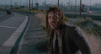 Movie still from “Being John Malkovich” (1999), directed by Spike Jonze – A man in a suit and tie on the side of the road; Close Up shot, Low angle