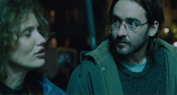 Movie still from “Being John Malkovich” (1999), directed by Spike Jonze – A man and a woman standing next to each other; Close Up shot, Over the shoulder angle