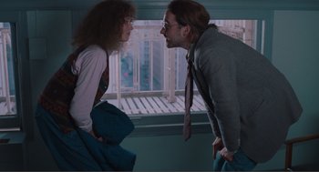 Movie still from “Being John Malkovich” (1999), directed by Spike Jonze – A man and a woman standing next to each other in front of a window; Medium shot, Over the shoulder angle