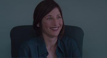 Movie still from “Being John Malkovich” (1999), directed by Spike Jonze – A woman sitting in an office chair smiling for the camera; Close Up shot, Over the shoulder angle