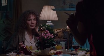 Movie still from “Being John Malkovich” (1999), directed by Spike Jonze – A woman sitting at a table with a vase of flowers; Medium shot, Over the shoulder angle