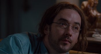Movie still from “Being John Malkovich” (1999), directed by Spike Jonze – A person wearing glasses and a blue shirt; Close Up shot, Over the shoulder angle