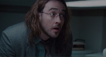 Movie still from “Being John Malkovich” (1999), directed by Spike Jonze – A person with long hair wearing glasses; Close Up shot, High angle