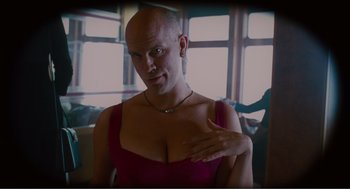 Movie still from “Being John Malkovich” (1999), directed by Spike Jonze – A bald man in a red shirt is posing for a picture; Close Up shot, Low angle