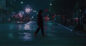 Movie still from “Being John Malkovich” (1999), directed by Spike Jonze – A person is walking on a wet street at night; Wide shot, Low angle