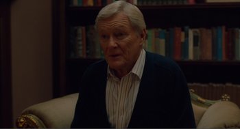 Movie still from “Being John Malkovich” (1999), directed by Spike Jonze – An older man sitting in front of a book shelf; Medium shot, Over the shoulder angle