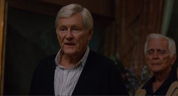 Movie still from “Being John Malkovich” (1999), directed by Spike Jonze – An older man wearing a black jacket and a white shirt; Close Up shot, Over the shoulder angle