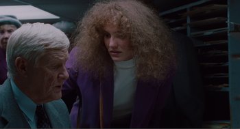 Movie still from “Being John Malkovich” (1999), directed by Spike Jonze – A woman with long curly hair is talking to an older man; Medium shot, Over the shoulder angle
