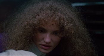 Movie still from “Being John Malkovich” (1999), directed by Spike Jonze – A person with long curly hair; Close Up shot, Over the shoulder angle