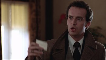 Movie still from “Being There” (1979), directed by Hal Ashby – A man in a brown jacket holding a white card; Close Up shot, Over the shoulder angle