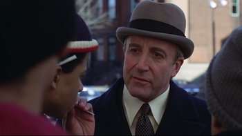 Movie still from “Being There” (1979), directed by Hal Ashby – A man in a suit and a hat talking on a phone; Close Up shot, Over the shoulder angle