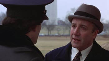 Movie still from “Being There” (1979), directed by Hal Ashby – A man wearing a suit and hat talking to another man; Close Up shot, Over the shoulder angle