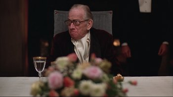 Movie still from “Being There” (1979), directed by Hal Ashby – An older man sitting at a table with a bouquet of flowers in front of him; Close Up shot, Over the shoulder angle
