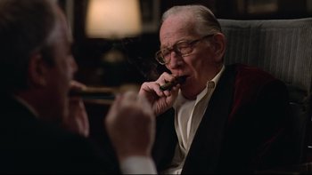 Movie still from “Being There” (1979), directed by Hal Ashby – An older man smoking a cigar while sitting in a chair; Close Up shot, Over the shoulder angle