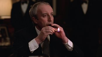 Movie still from “Being There” (1979), directed by Hal Ashby – A man in a suit and tie lighting a cigarette; Close Up shot, Low angle