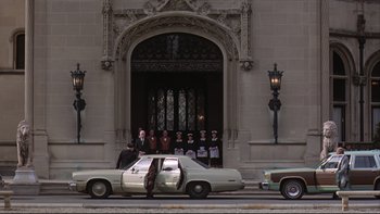 Movie still from “Being There” (1979), directed by Hal Ashby – A group of men standing in front of a building; Wide shot, High angle