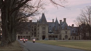 Movie still from “Being There” (1979), directed by Hal Ashby – A group of motorcycles driving down a street past a large building; Extreme Wide shot, High angle