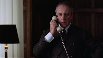 Movie still from “Being There” (1979), directed by Hal Ashby – A man in a suit and tie holding a phone to his ear; Close Up shot, Low angle