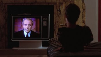 Movie still from “Being There” (1979), directed by Hal Ashby – A man sitting in front of a television; Close Up shot, Over the shoulder angle