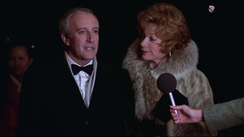 Movie still from “Being There” (1979), directed by Hal Ashby – A man and a woman are talking to a microphone; Close Up shot, Over the shoulder angle