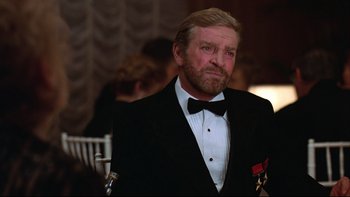 Movie still from “Being There” (1979), directed by Hal Ashby – A man in a tuxedo with a medal around his neck; Close Up shot, Over the shoulder angle