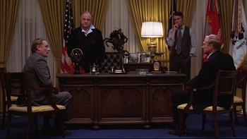 Movie still from “Being There” (1979), directed by Hal Ashby – Two men are sitting at a desk in front of an american flag; Wide shot, Low angle
