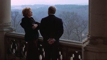 Movie still from “Being There” (1979), directed by Hal Ashby – A man and a woman standing on a balcony looking out over a forest; Wide shot, High angle