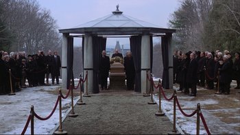 Movie still from “Being There” (1979), directed by Hal Ashby – A group of people standing around a gazebo with a casket on it; Wide shot, High angle