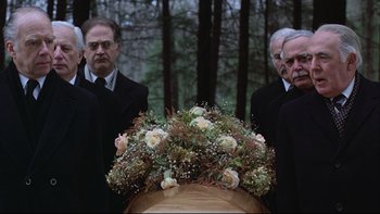Movie still from “Being There” (1979), directed by Hal Ashby – A group of men standing next to each other near flowers; Medium shot, Low angle