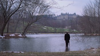 A man standing in the water in front of a large building