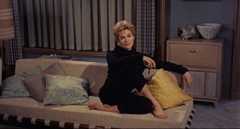 Movie still from “Bell, Book and Candle” (1976), directed by Hy Averback – A woman sitting on top of a couch in a living room; Medium shot, High angle