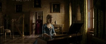 A woman in a blue dress sitting at a piano in a room