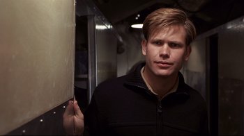 Movie still from “Below” (2002), directed by David Twohy – A man standing next to a white board in a room; Close Up shot, Over the shoulder angle
