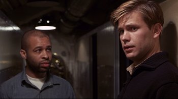 Movie still from “Below” (2002), directed by David Twohy – Two men standing next to each other in front of a building; Close Up shot, Over the shoulder angle