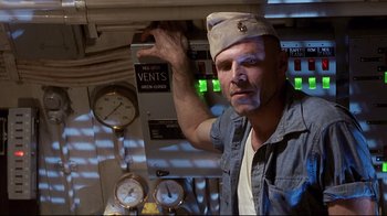 Movie still from “Below” (2002), directed by David Twohy – A man wearing a hat standing in front of an electrical box; Medium shot, Low angle