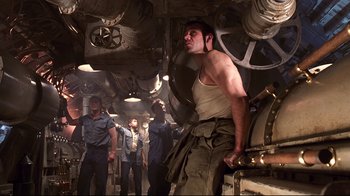 Movie still from “Below” (2002), directed by David Twohy – A group of men standing around in a room; Medium shot, Low angle