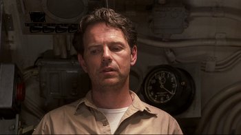 Movie still from “Below” (2002), directed by David Twohy – A person in a room with a clock on the wall; Close Up shot, Low angle