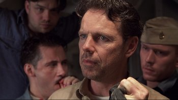 Movie still from “Below” (2002), directed by David Twohy – A man with blue eyes is looking at the camera while two other men look at him; Close Up shot, Low angle