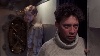 Movie still from “Below” (2002), directed by David Twohy – A man in a white sweater standing next to another man in a white sweater; Close Up shot, Over the shoulder angle