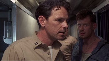 Movie still from “Below” (2002), directed by David Twohy – A man in a tan shirt and a man in a blue shirt; Close Up shot, Over the shoulder angle